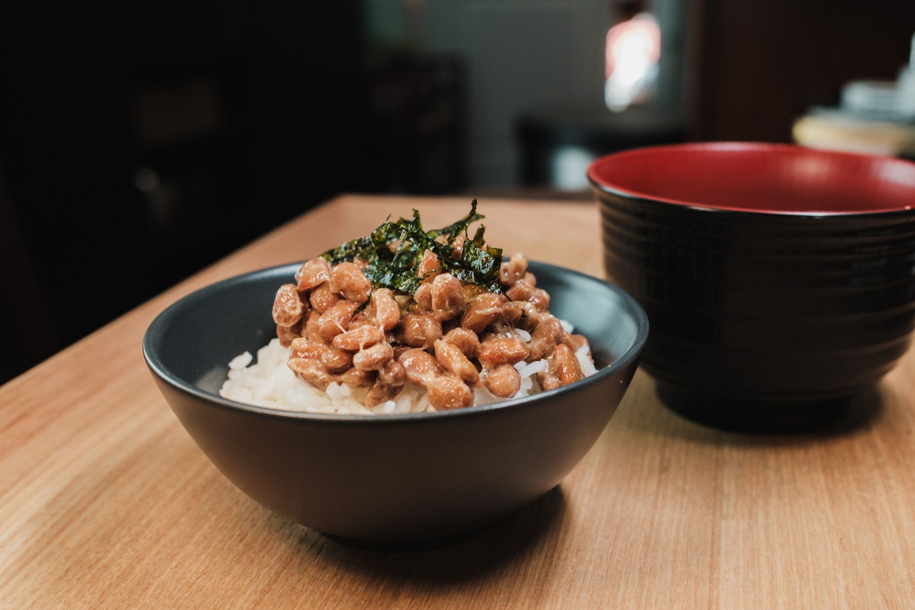 Trois bols japonais contenant du miso, du tempeh tranché et du natto sur une table en bois