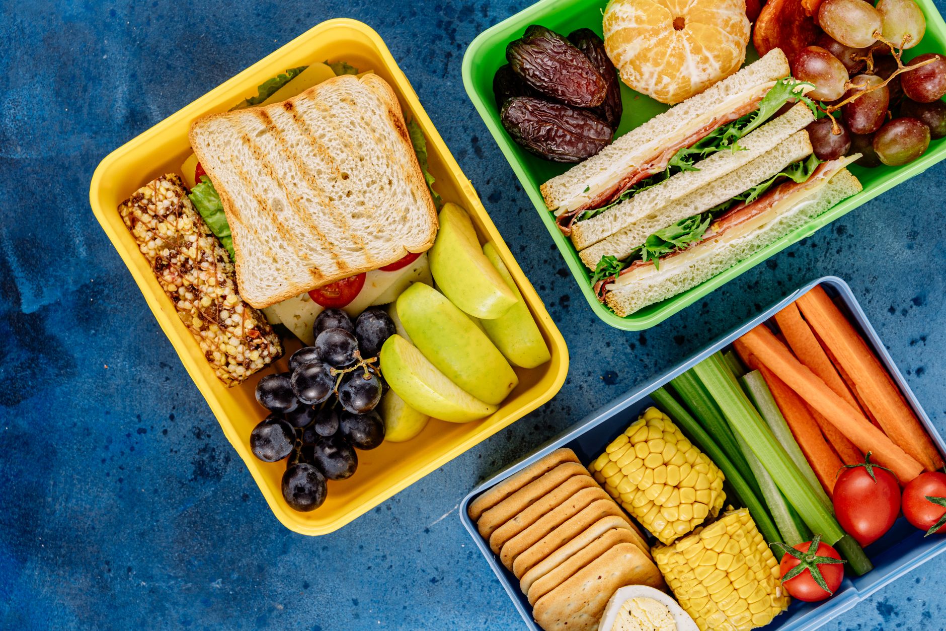 Boîte à goûter réutilisable garnie de biscuits maison, fruits et fromage à côté d'une gourde en inox
