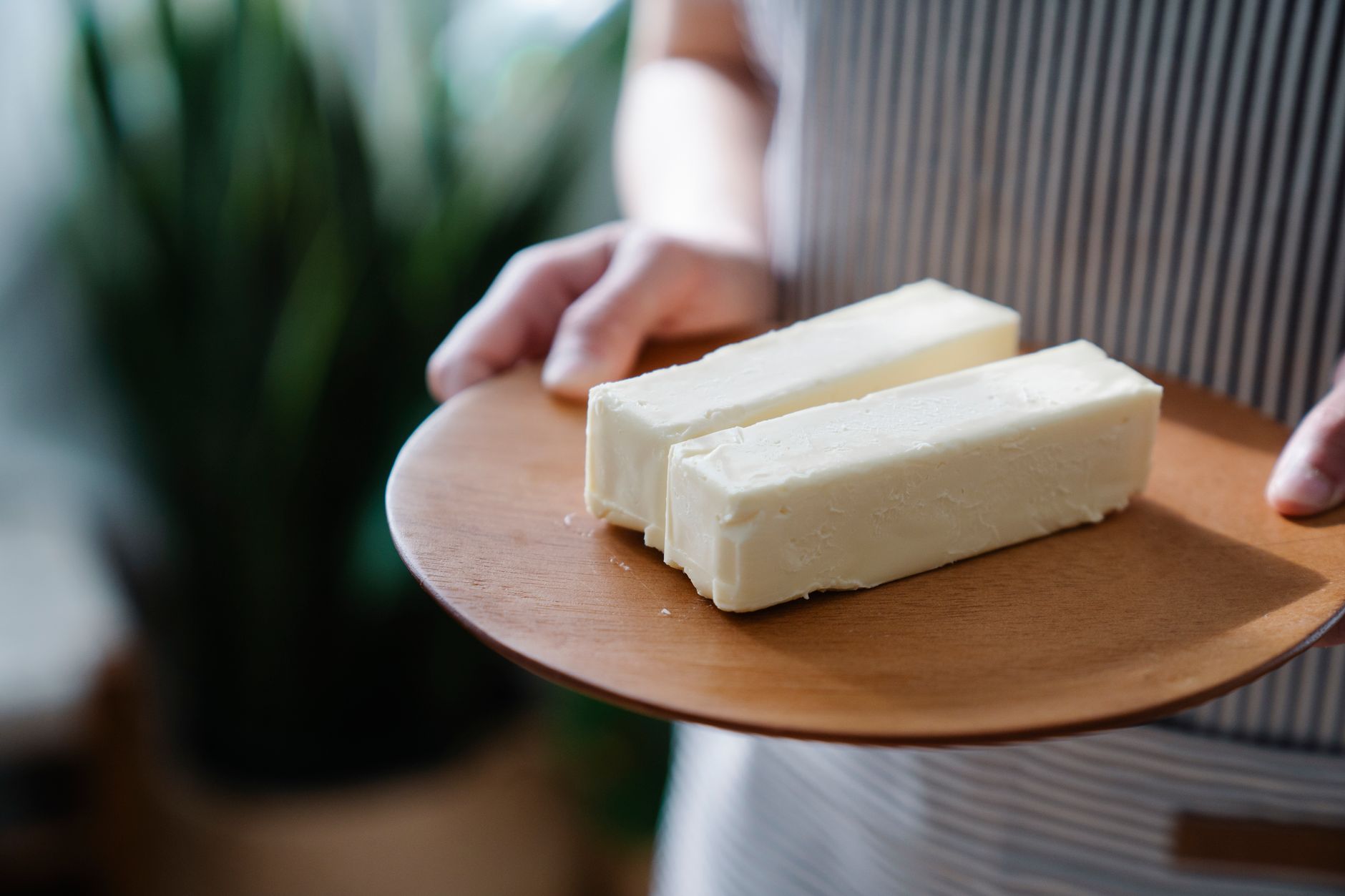 Motte de beurre maison et pot de ghee doré sur une table en bois