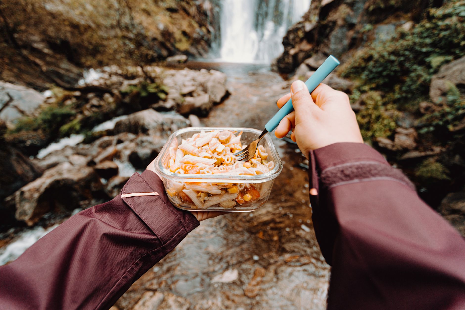 Repas de randonnée équilibré posé sur une table de camping avec sac à dos et montagnes en arrière-plan