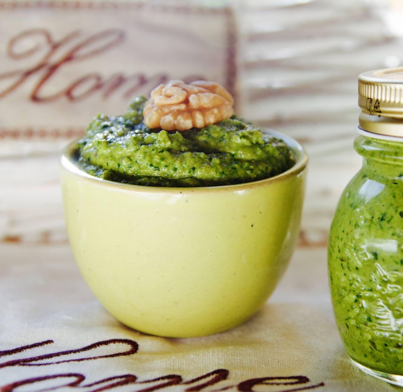 Plusieurs bols de pestos maison colorés aux herbes et fanes variées sur une table en bois