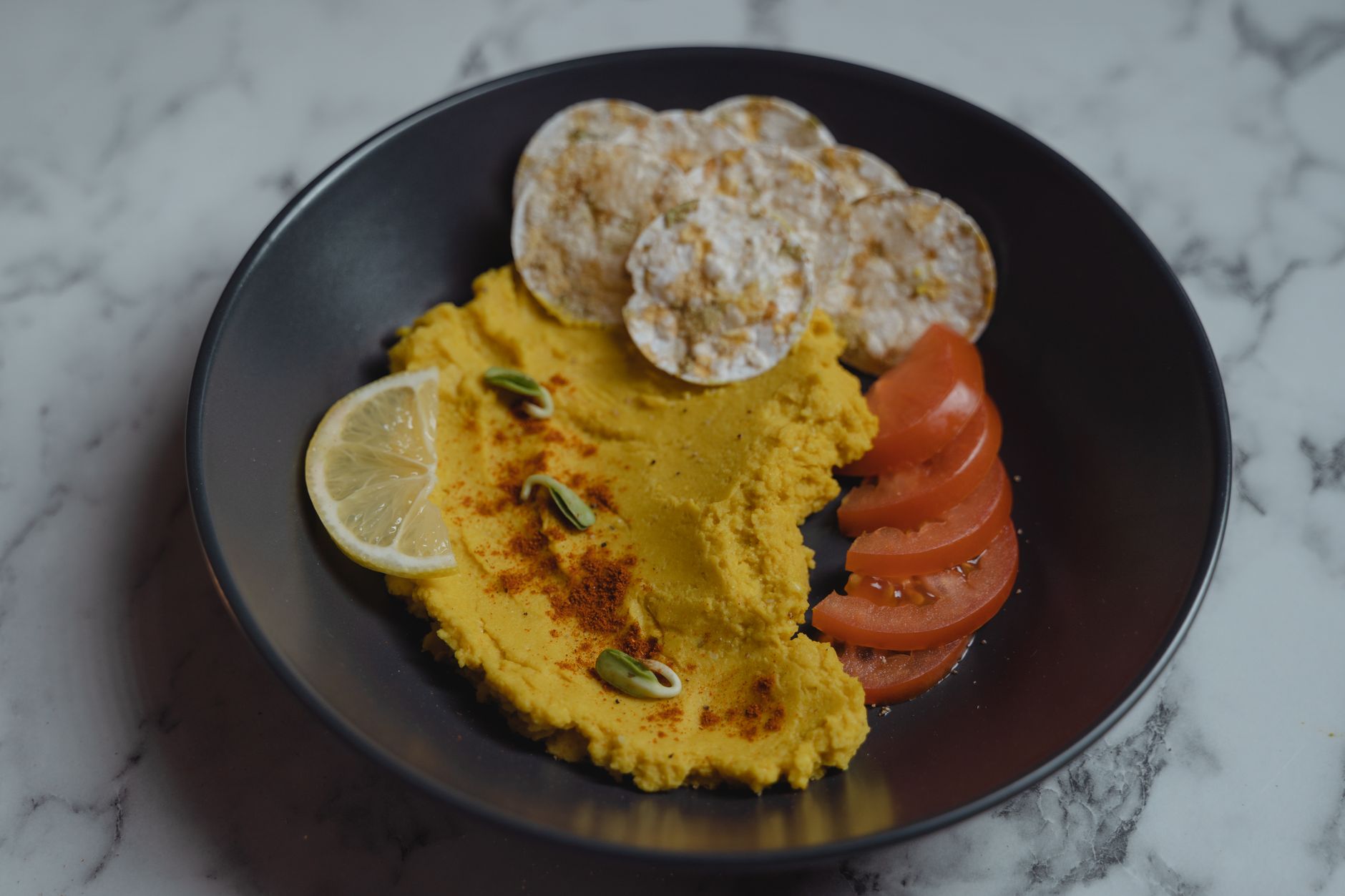 Plateau d'apéro avec plusieurs bols de hummus et tartinades de légumineuses colorées, crudités et pain pita